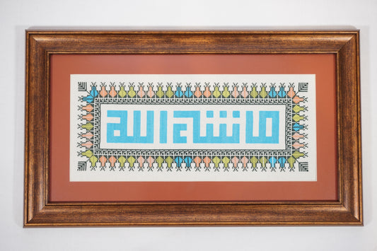 Handmade Palestinian tatreez framed artwork with “ما شاء الله” (What God has willed) in blue embroidery, surrounded by colorful floral patterns, Islamic home decor