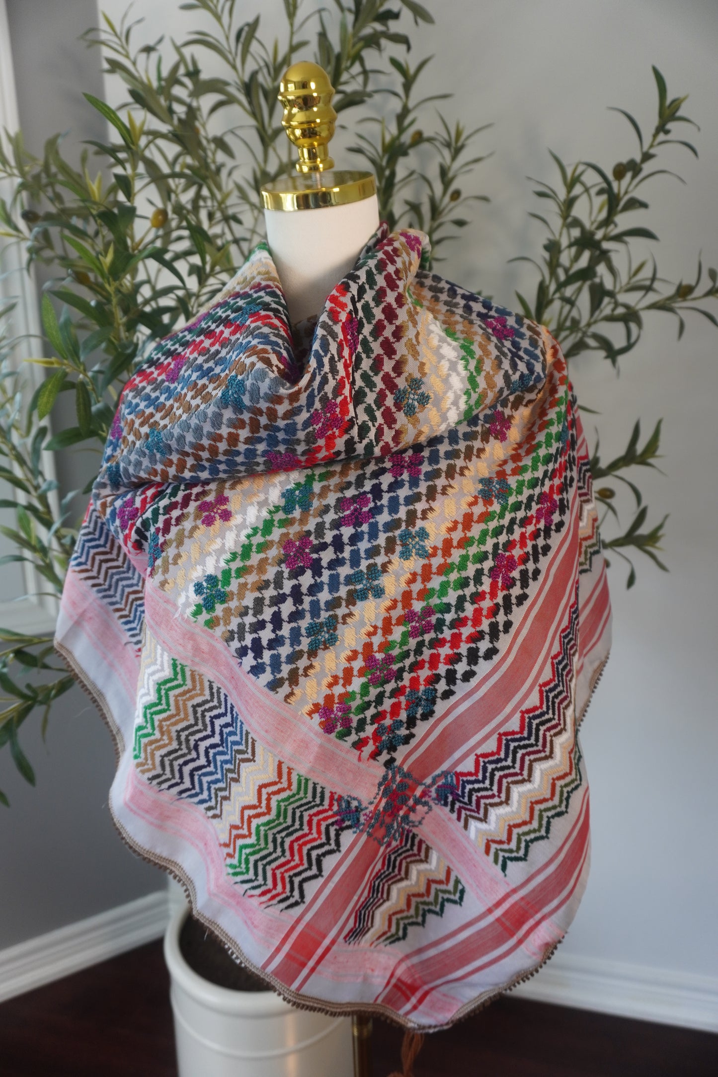 A handmade colorful kofea with a prominent red base, adorned with bright embroidered patterns, showcasing unique craftsmanship and a striking design.
