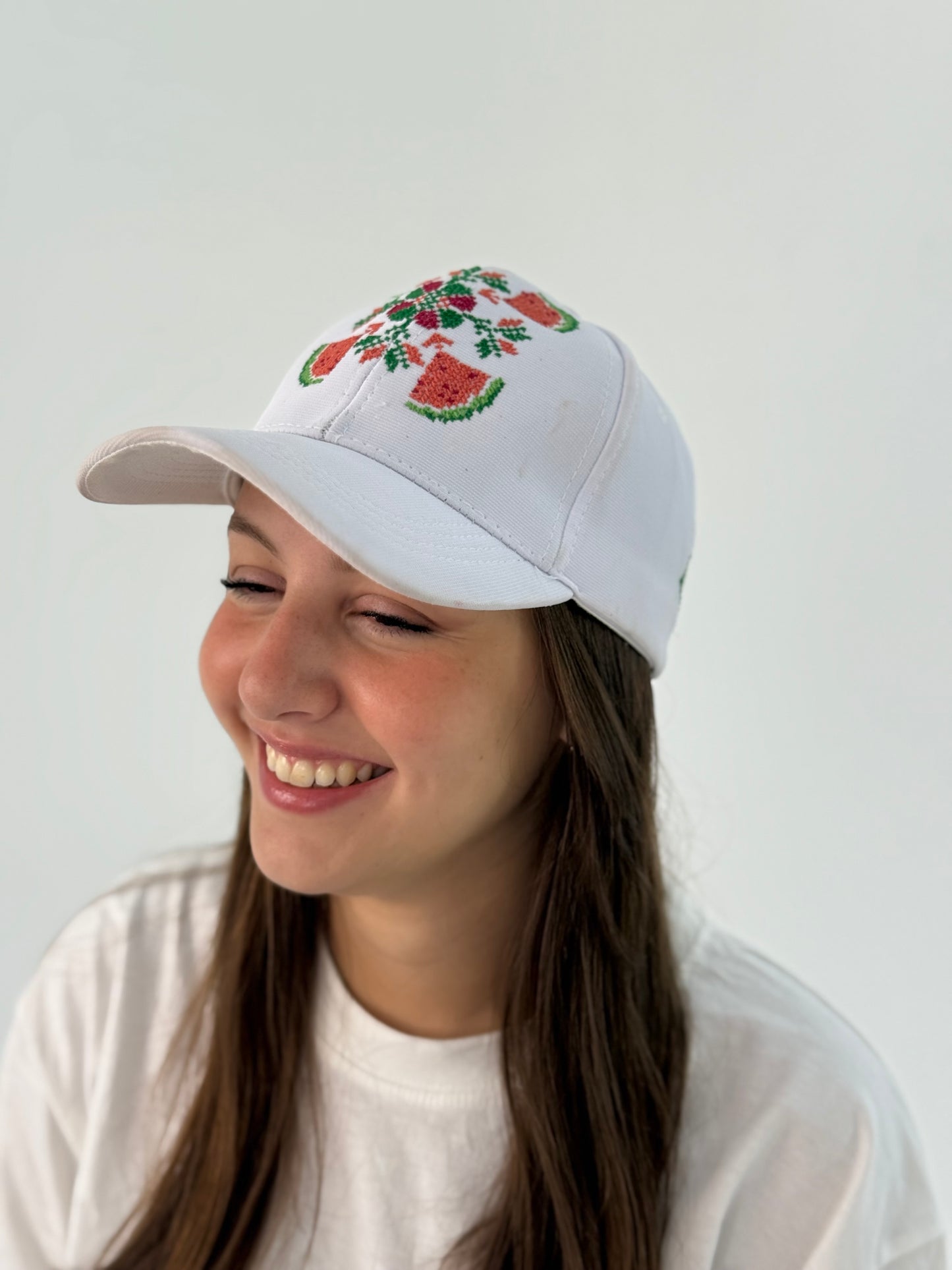 White hat with an embroidered design of flowers and watermelon.