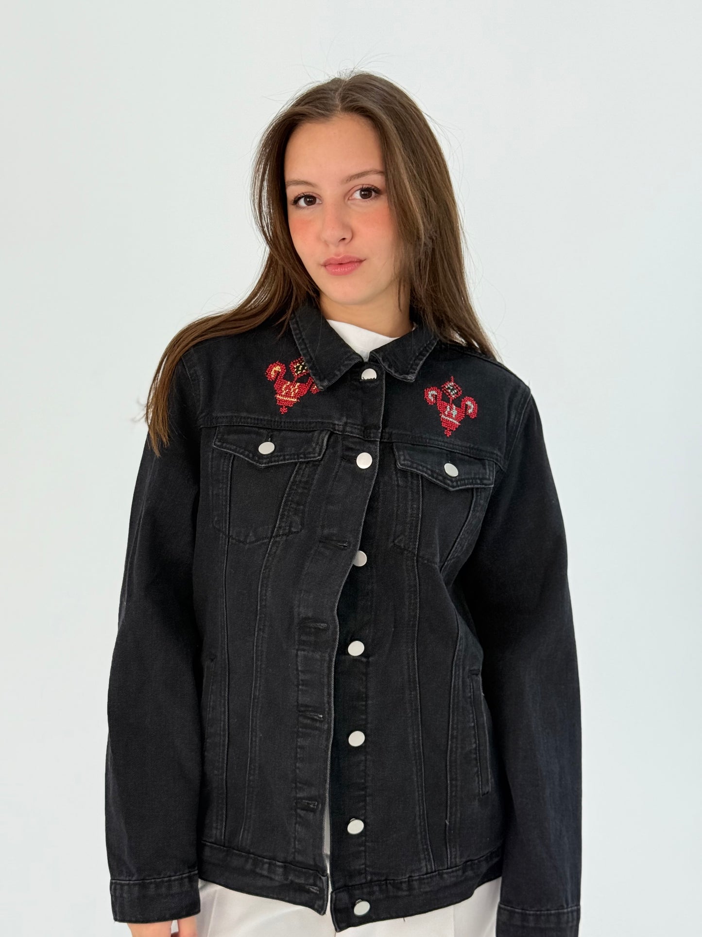 Black jeans jacket with bright blue, orange, yellow, and red embroidery on the front and back, showcasing a passionate and detailed design.