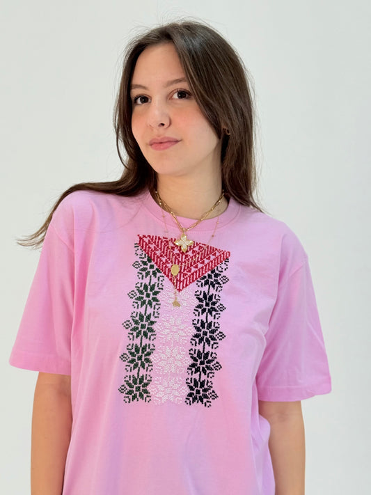 Pink cotton t-shirt featuring hand-embroidered Palestinian flag colors in traditional tatreez pattern, youth cultural heritage wear