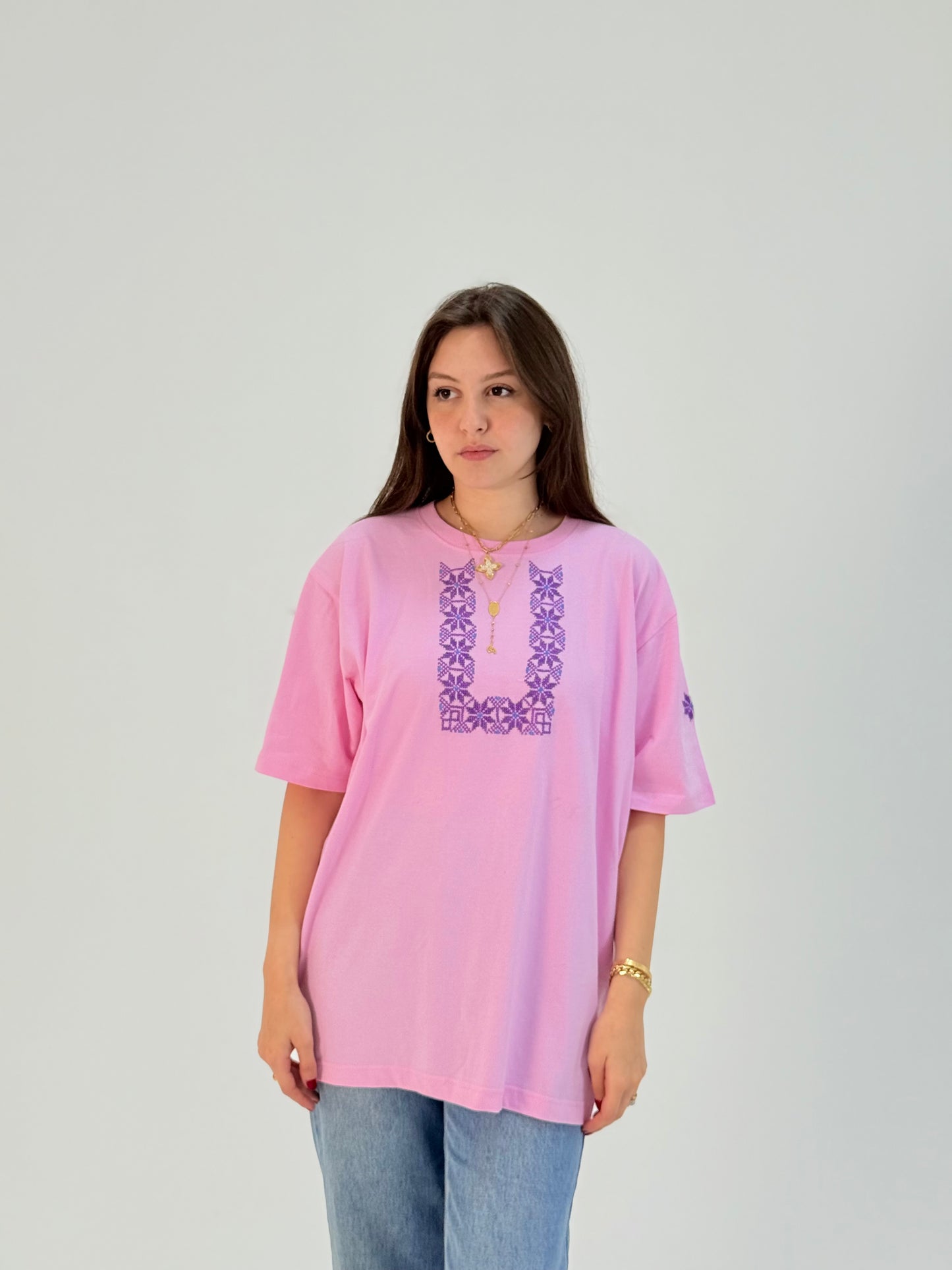 Cotton t-shirts in light blue and pink with U-shaped Palestinian tatreez embroidery, modeled with jeans, handmade by women artisans