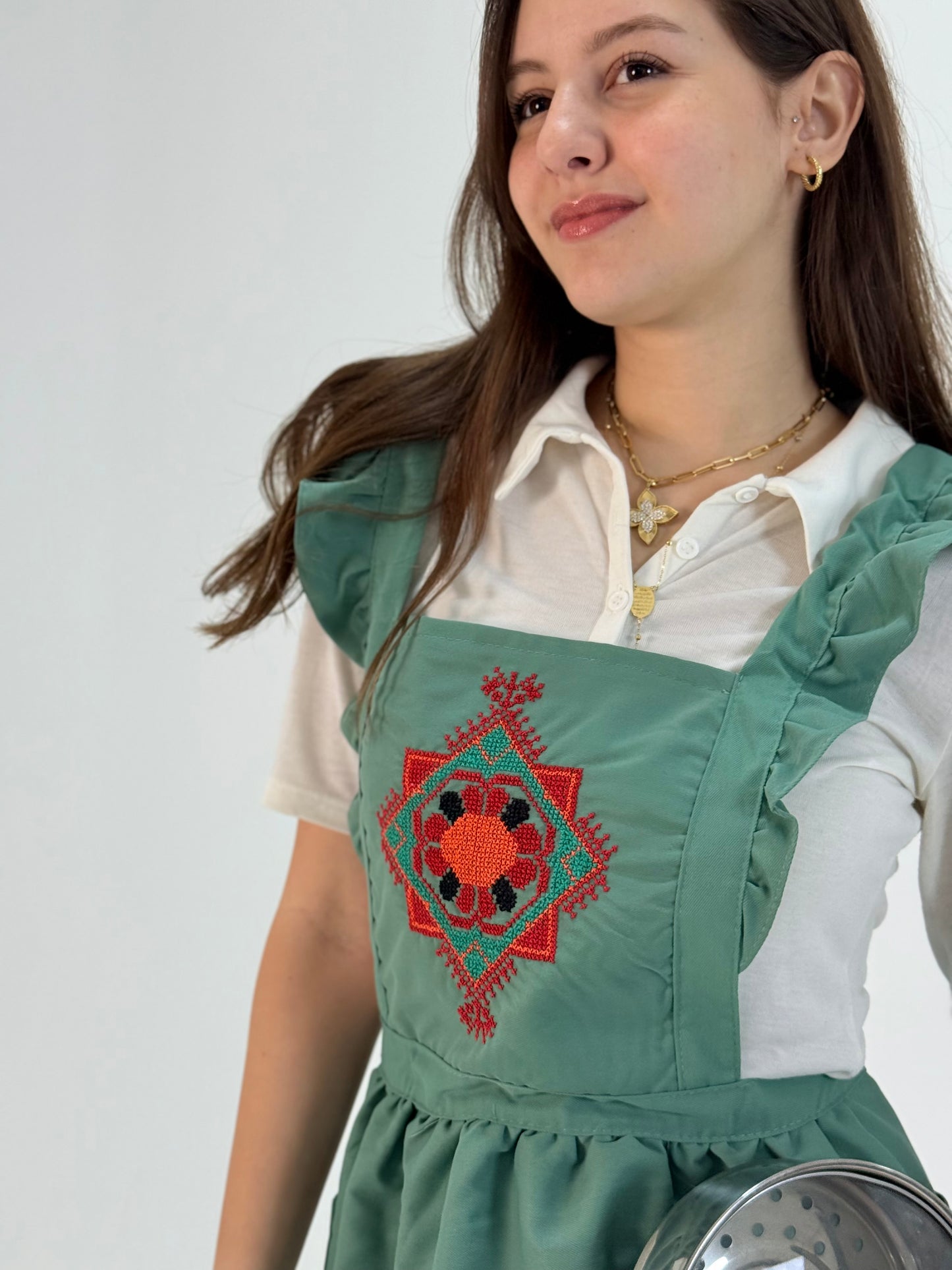 Light green waterproof poplin apron with handmade floral embroidery, crafted by women artisans.