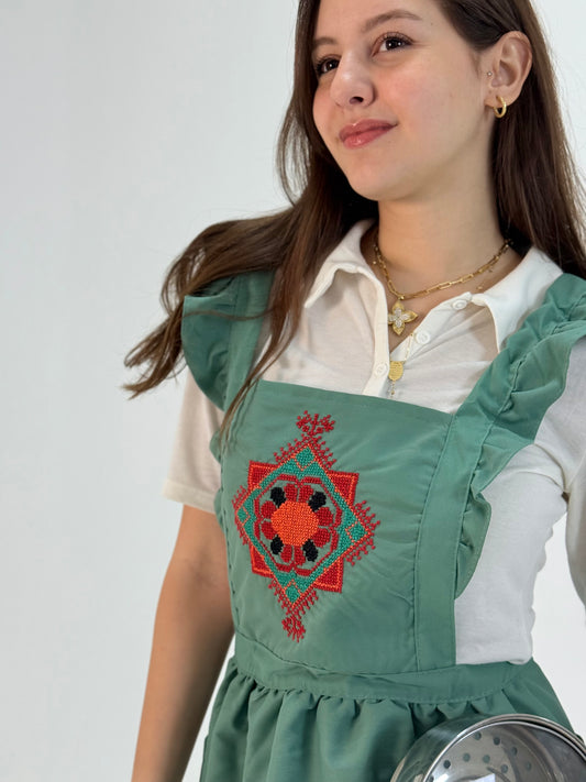 Light green waterproof poplin apron with handmade floral embroidery, crafted by women artisans.