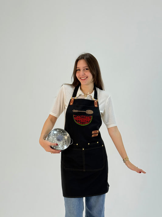 Black waterproof apron with hand-embroidered watermelon map design, made by women artisans.