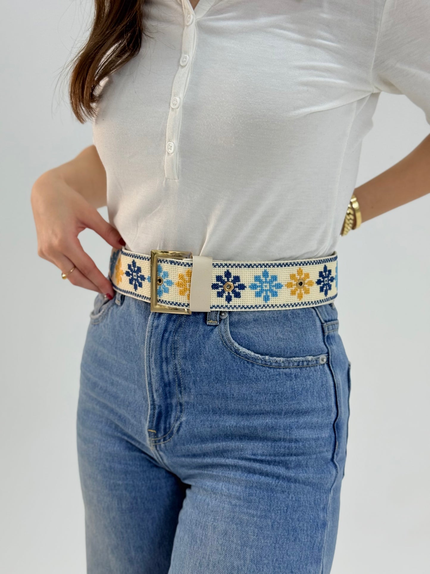 Handmade adjustable belt with floral tatreez embroidery in blue and yellow on cream, worn with jeans