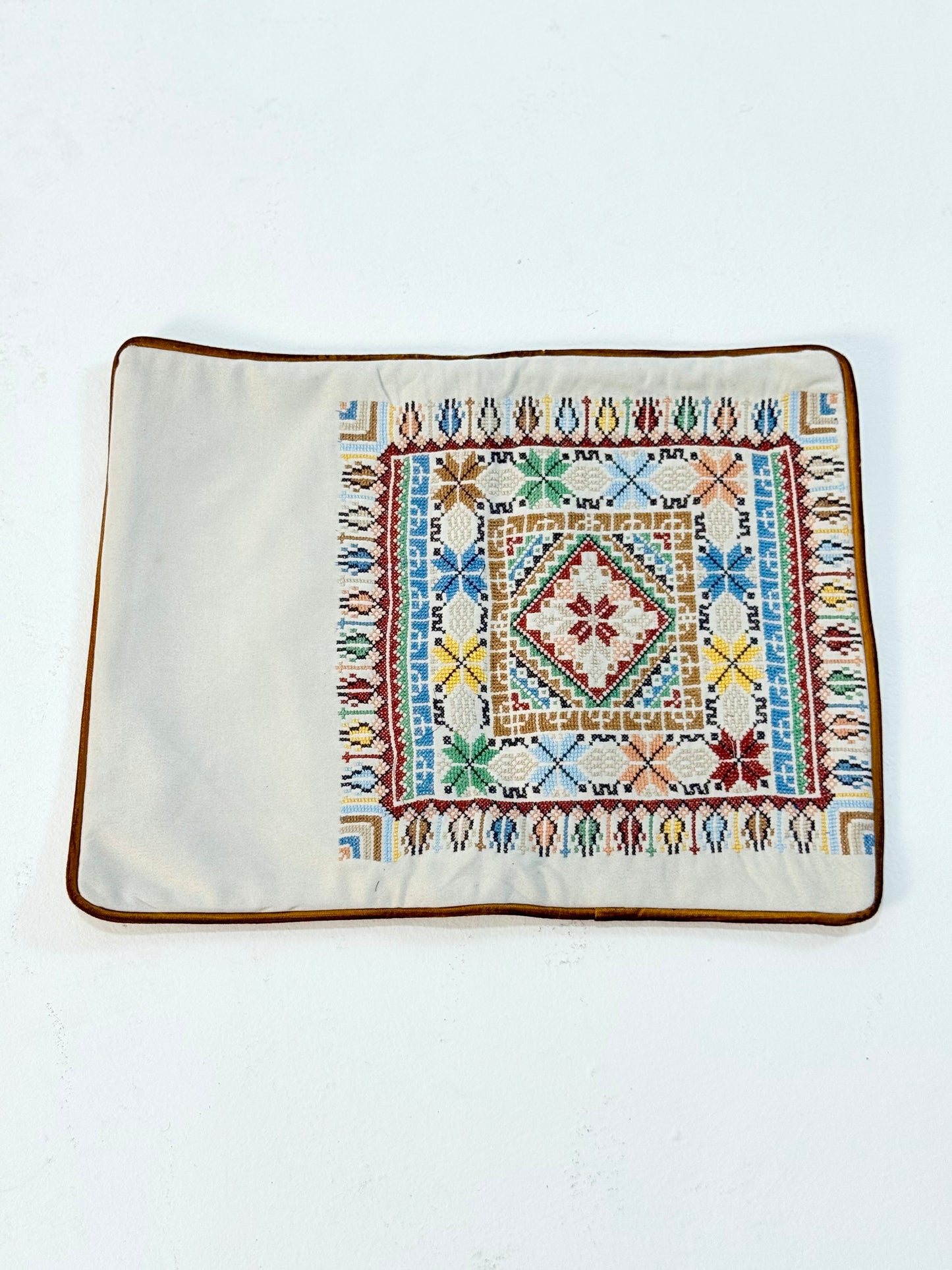 Hand-embroidered rectangular cushion covers featuring vibrant Palestinian tatreez geometric motifs on beige and turquoise backgrounds, crafted by women artisans from Palestine and Jordan to preserve heritage and support their livelihoods.