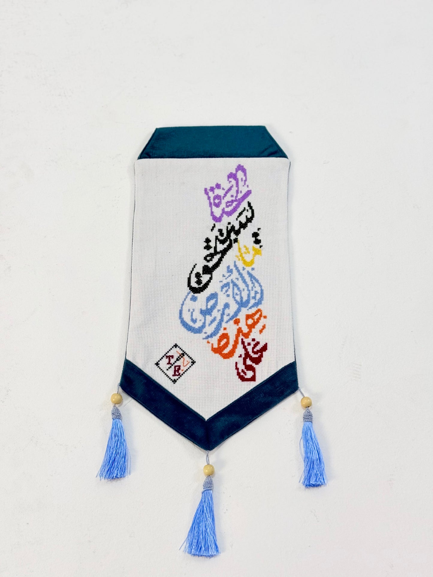 Handmade embroidered wall hanging with Arabic calligraphy “على هذه الأرض ما يستحق الحياة,” crafted by Palestinian women artisan