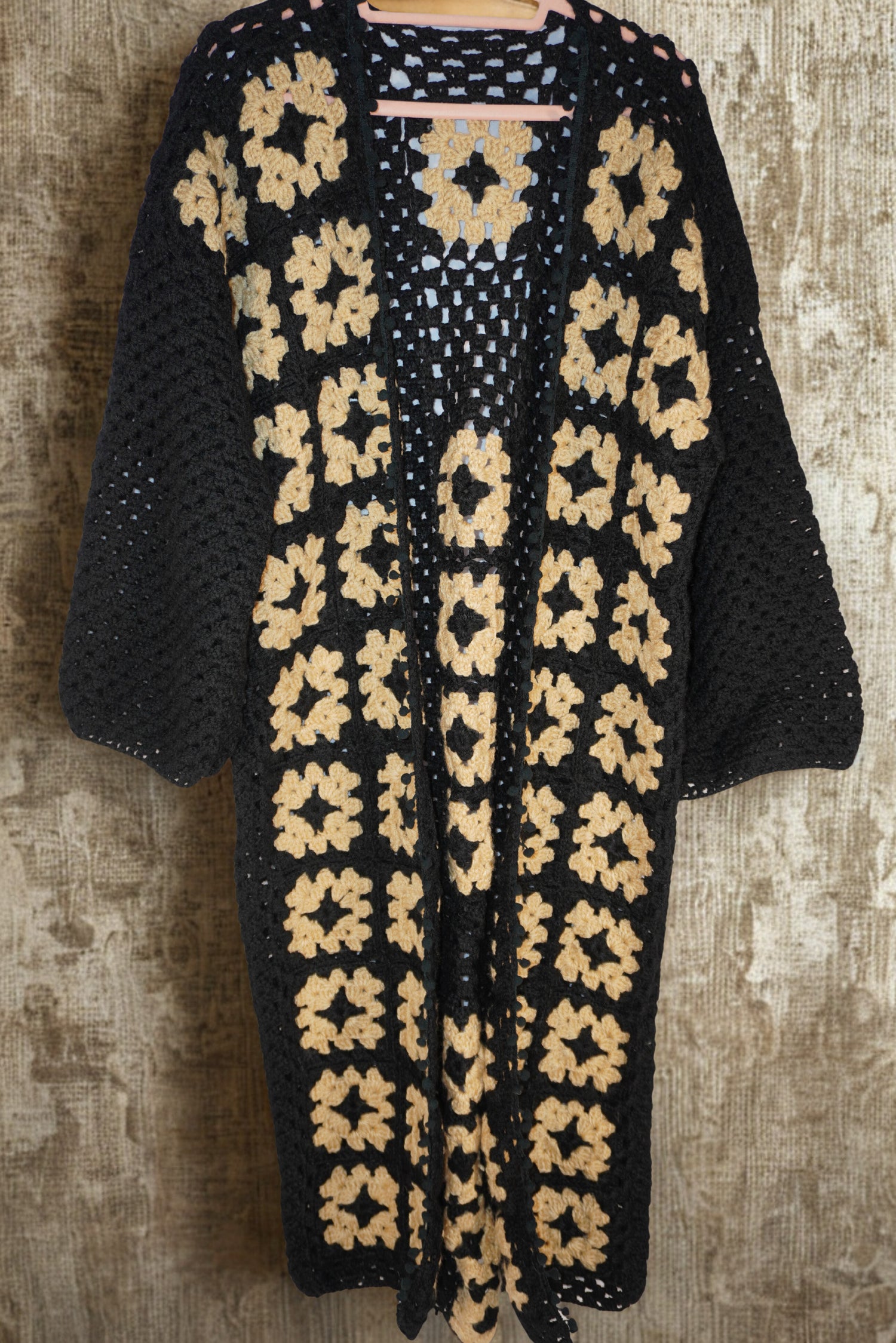Handmade black crochet cardigan with cream floral motifs, crafted by women artisans.
