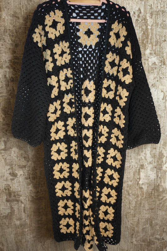Handmade black crochet cardigan with cream floral motifs, crafted by women artisans.
