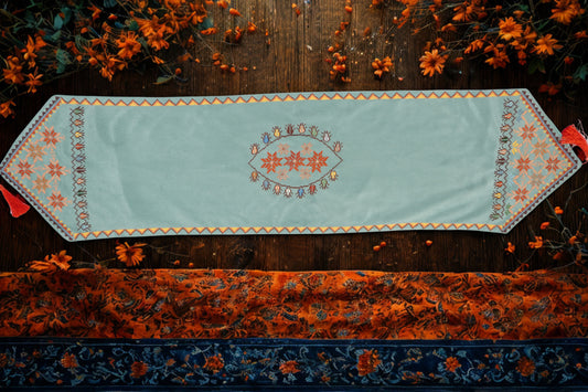 Hand-embroidered suede table runners featuring elegant Palestinian tatreez floral and geometric designs on turquoise and beige backgrounds, handmade by Palestinian and Jordanian women artisans seeking financial independence while preserving regional heritage.