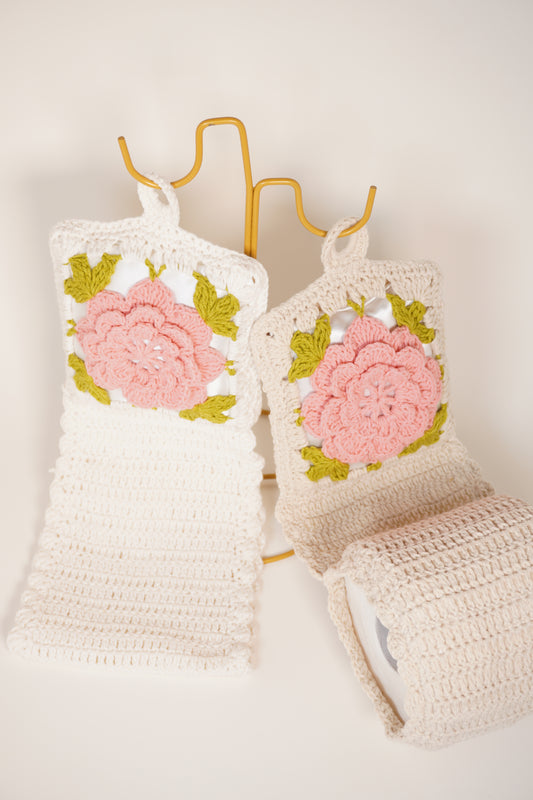 Hand-crocheted toilet paper roll cover with pink floral design, handmade crochet bathroom decor for organizing toilet rolls with elegance
