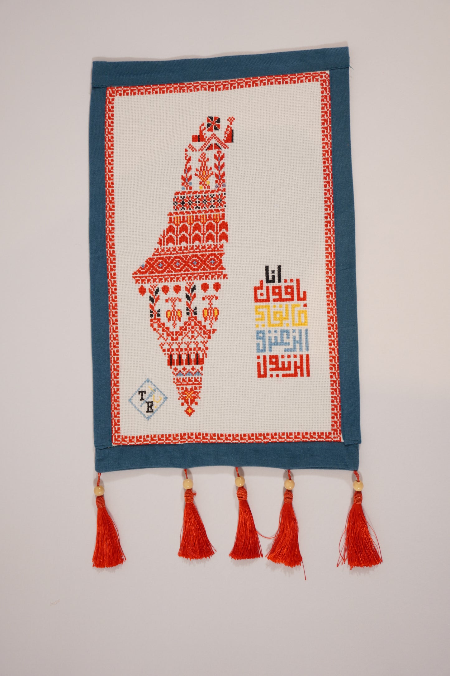 Handmade embroidered Mo’allaqa wall hanging with the map of Palestine in red tatreez patterns, crafted by Palestinian women artisans.
