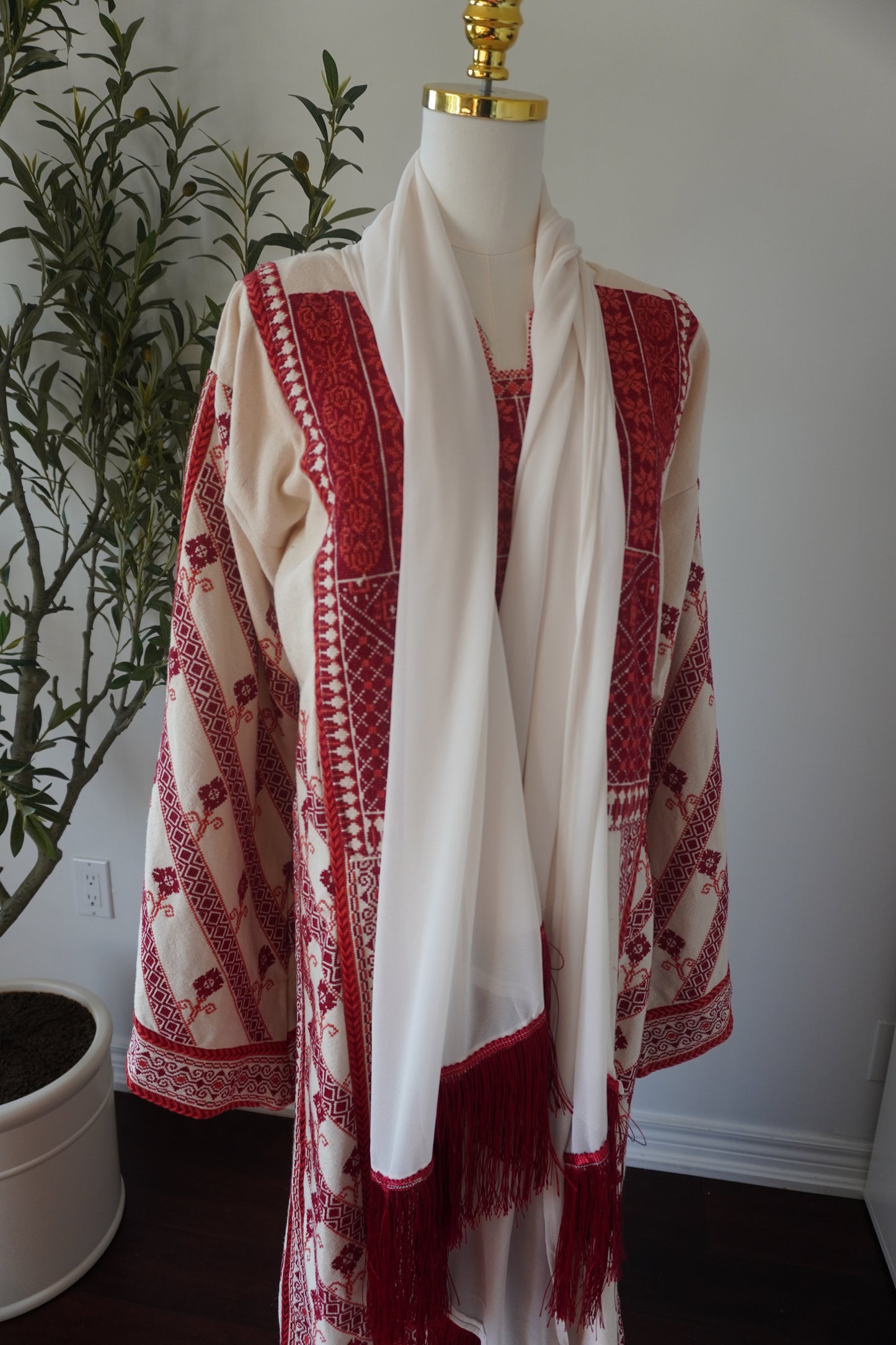 Hand-made off-white thoub from Yata Al Khalil with vibrant red and orange Palestinian embroidery. Comes with an off-white shawl with sharasheeb and a silk belt.