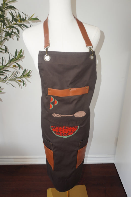 Brown apron with spoon and watermelon slices embroidered on the pocket and a colorful watermelon design on the lower part, perfect for kitchen or barbecue gatherings."