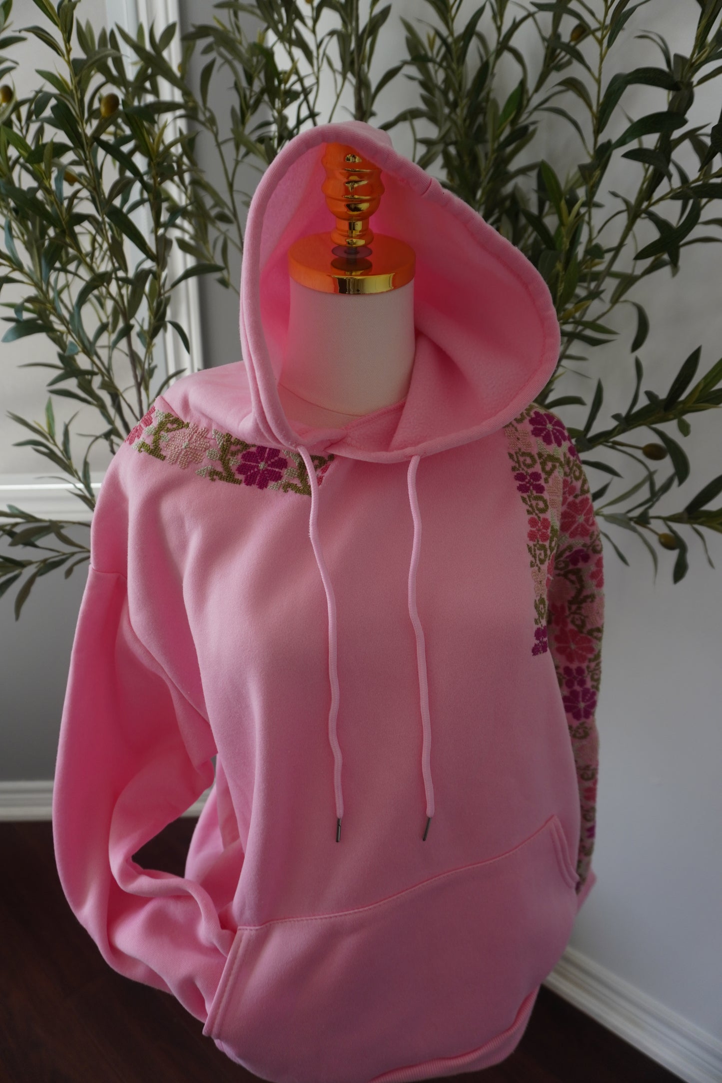 Medium pink hoodie adorned with beautiful embroidered flowers, crafted from a cotton and polyester blend.