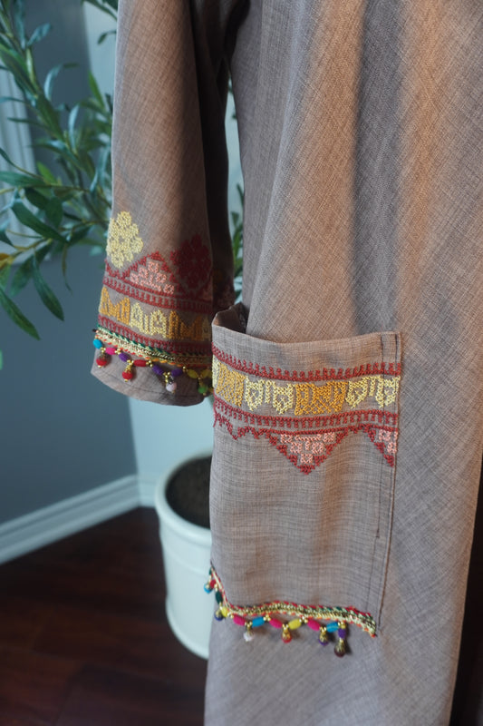 Handmade fusion thoub in beige featuring exquisite Tatreez embroidery crafted with DMC thread, made from heavy linen, showcasing a blend of traditional artistry and contemporary design.