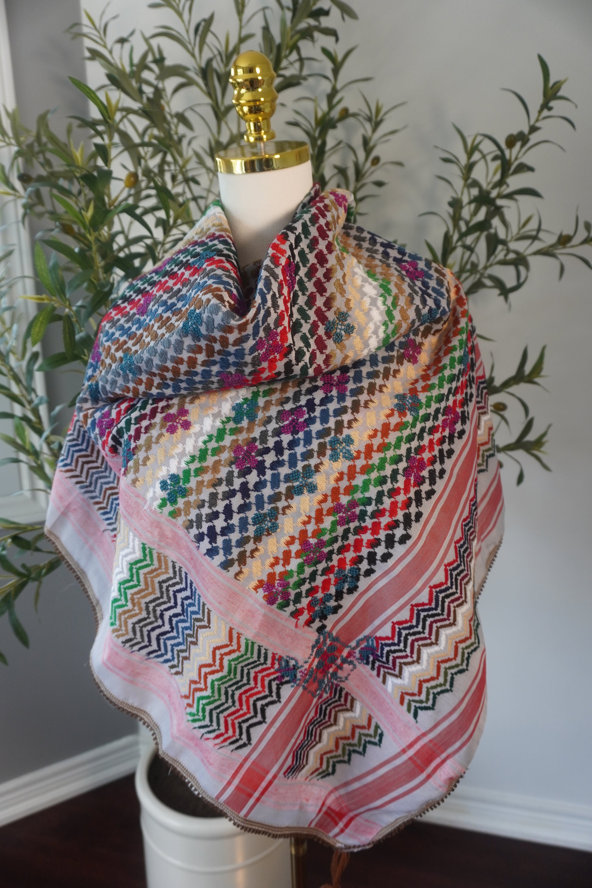 A handmade colorful kofea with a prominent red base, adorned with bright embroidered patterns, showcasing unique craftsmanship and a striking design.
