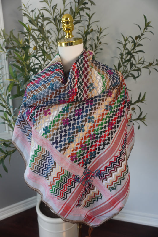 A handmade colorful kofea with a prominent red base, adorned with bright embroidered patterns, showcasing unique craftsmanship and a striking design.