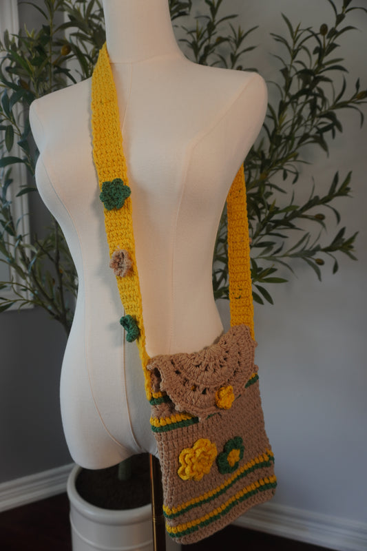 Handmade crochet phone case featuring a vibrant design of flower granny squares in shades of green, yellow, and beige. The case includes a matching strap for easy carrying, perfect for daily use.