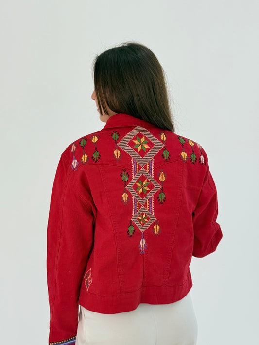 Red jeans jacket with blue, orange, and green embroidery on the front and back, showcasing a vibrant and stylish design.