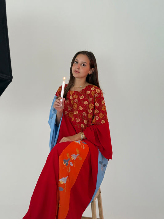 Handmade colorful layered abaya in soft linen, featuring light blue, red, and orange colors with floral designs and Palestinian embroidery.