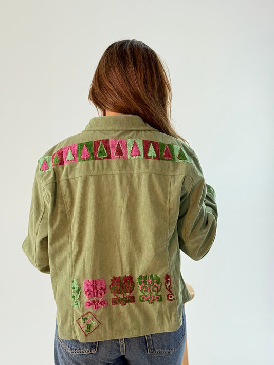 A light green denim jacket featuring beautiful handmade colorful embroidery on the back, showcasing unique artisan style and craftsmanship.