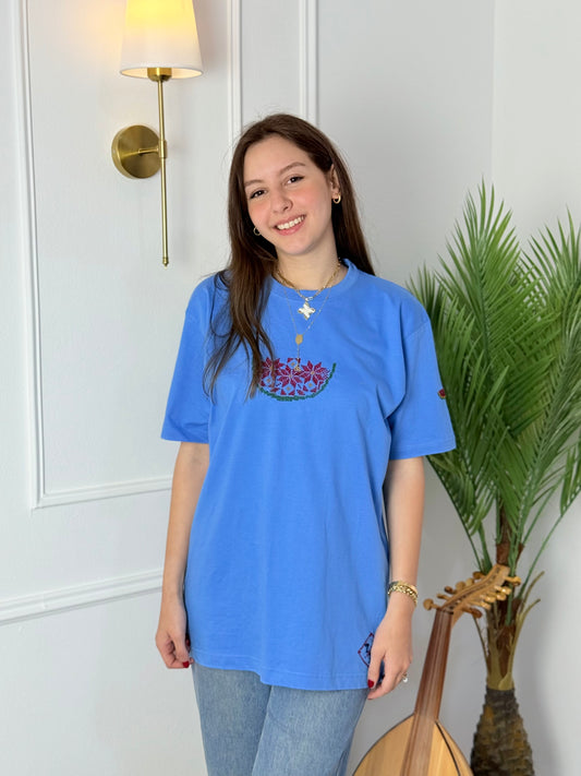 Light blue cotton t-shirt with handmade Palestinian watermelon embroidery, modeled with jeans, crafted by women artisans