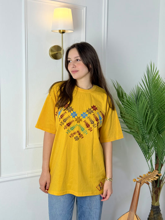 Yellow cotton t-shirt with colorful Kanaan star tatreez embroidery, modeled with jeans, handmade by women artisans