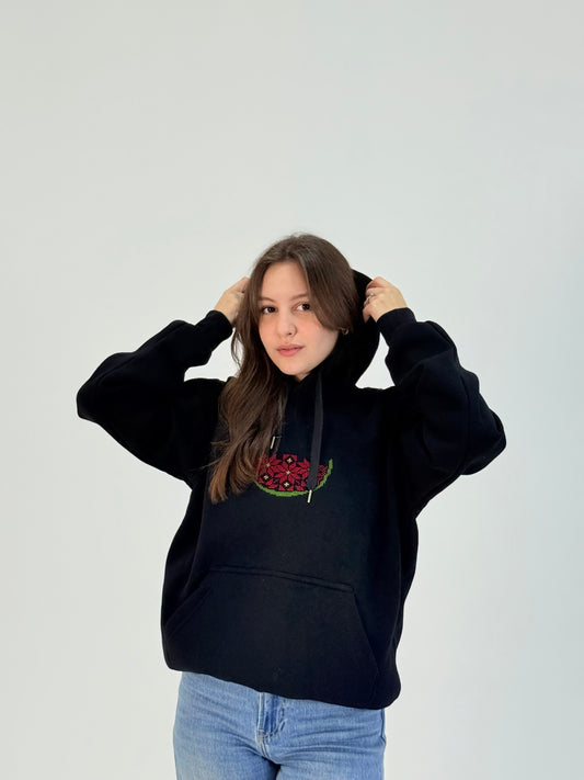 Black cotton hoodie with hand-embroidered watermelon design in red and green tatreez, modeled with jeans, handmade by women artisans