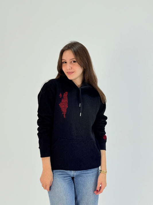 Black cotton hoodie with hand-embroidered red Palestinian map and tatreez design, modeled with jeans, handmade by women artisans