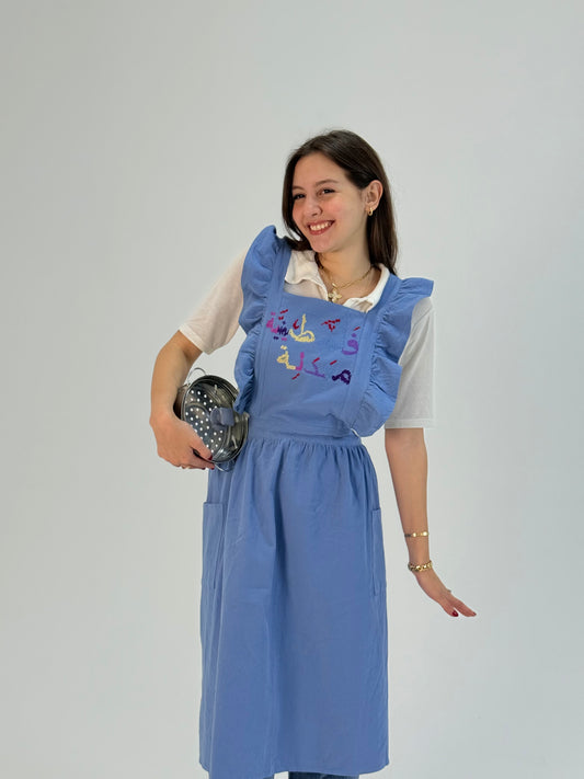 Handmade blue waterproof apron with Falasteeniya Maadale Palestinian embroidery, crafted by women artisans.