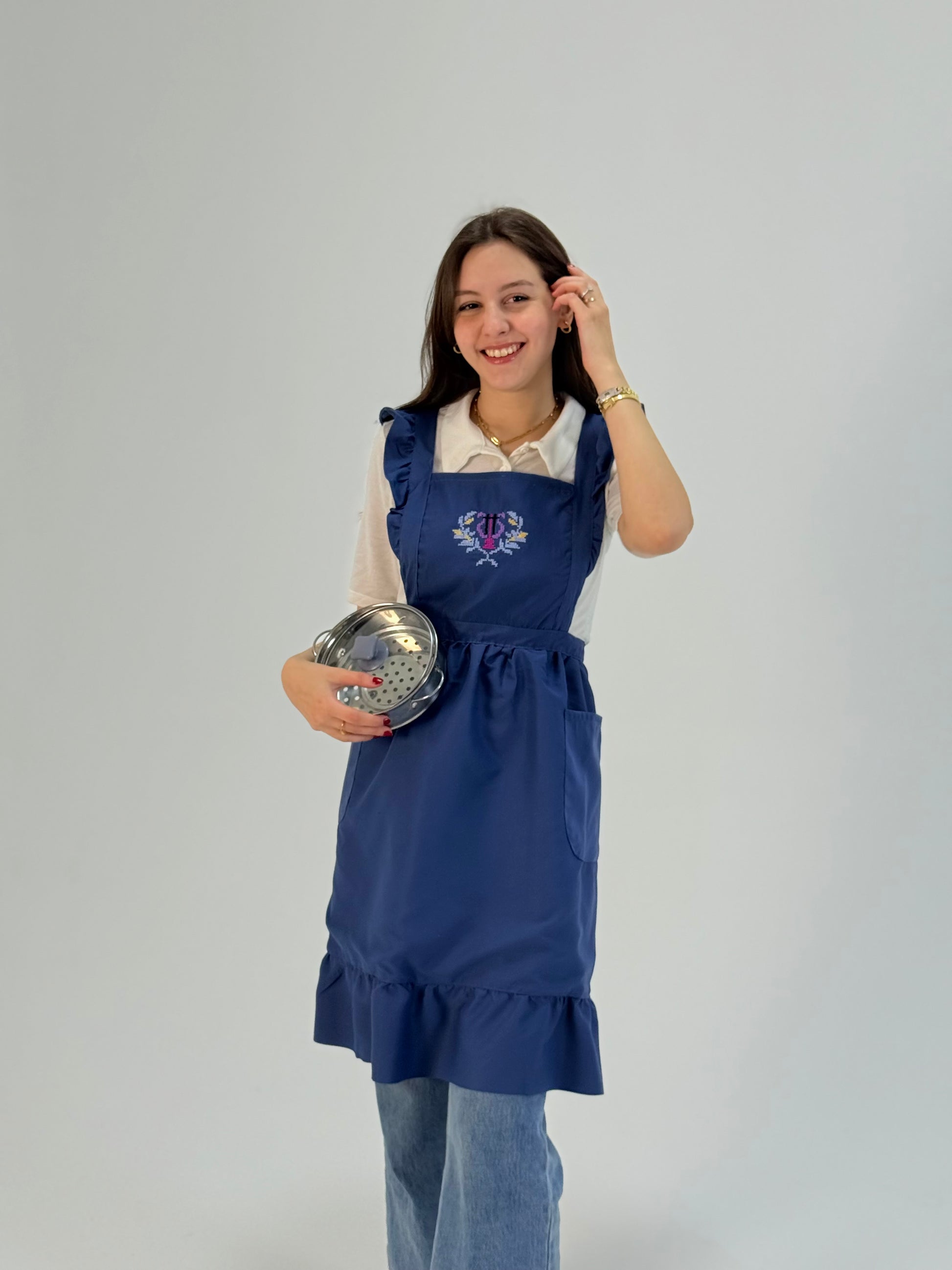 Blue waterproof apron with handmade Sanable floral embroidery, crafted by women artisans.