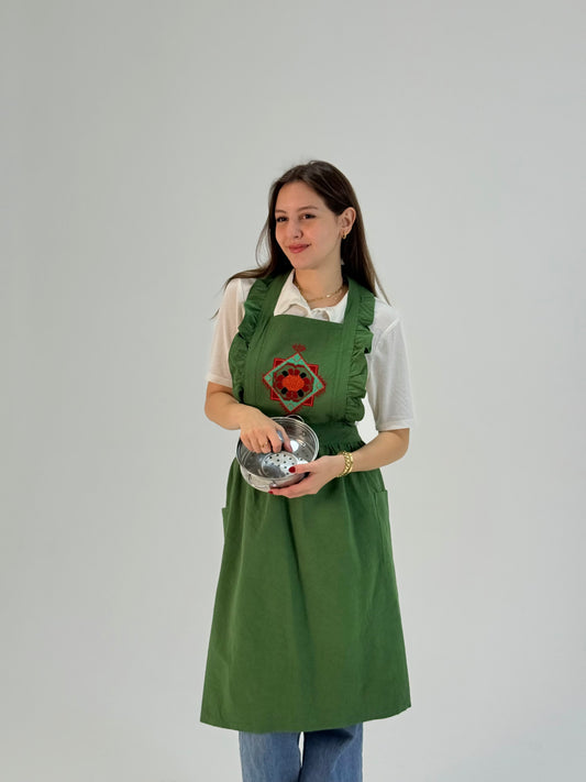 Handmade green waterproof apron with floral embroidery, crafted by Palestinian women artisans, perfect for kitchen and cooking use.