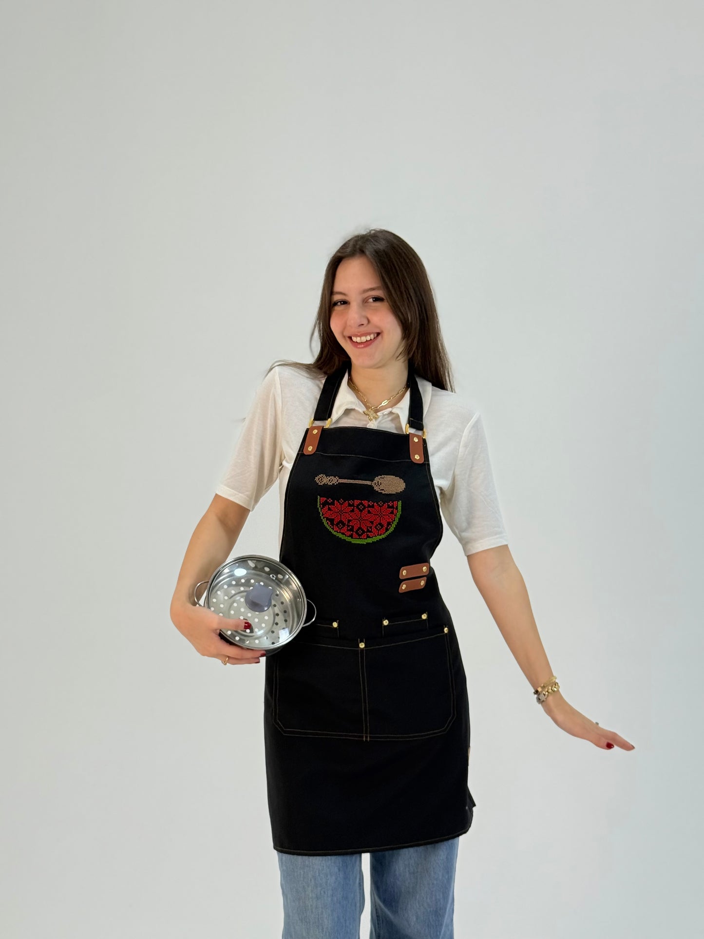 Black waterproof apron with hand-embroidered watermelon map design, made by women artisans.
