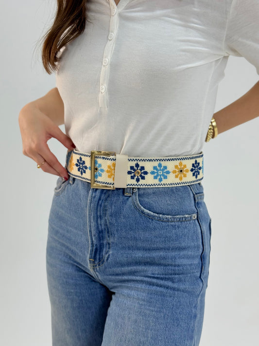 Handmade adjustable belt with floral tatreez embroidery in blue and yellow on cream, worn with jeans
