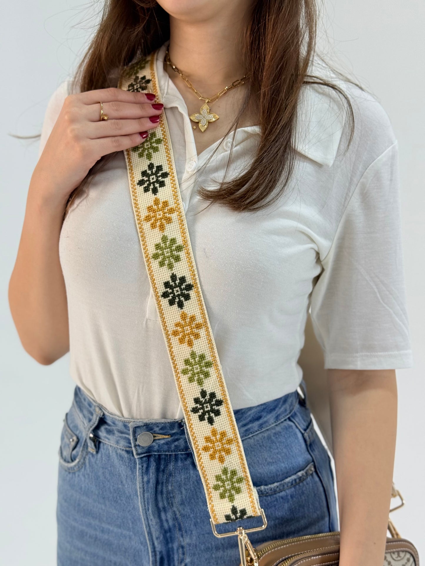 Handmade adjustable bag strap with traditional Palestinian floral tatreez embroidery in yellow and black on cream background
