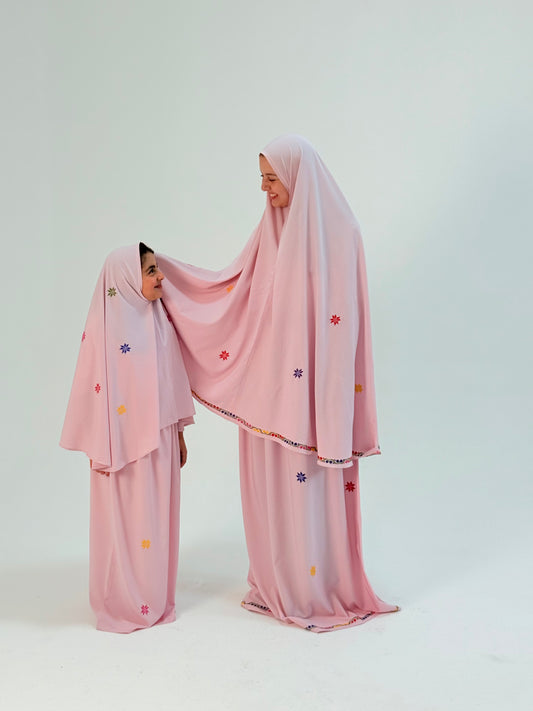Pink adult prayer clothes with hand-embroidered floral motifs, handmade by women artisans in Palestine and Jordan.