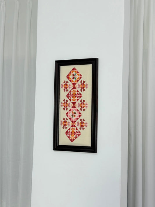 Handmade Palestinian embroidery wall art with red geometric patterns, framed and crafted by Palestinian women artisans.