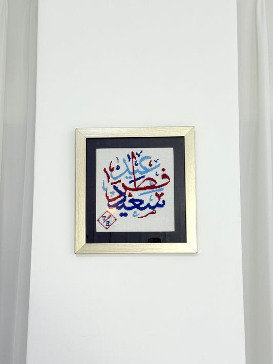 Handmade embroidered wall art with “عيد سعيد” (Happy Eid) in Arabic calligraphy, framed and crafted by Palestinian women artisans.