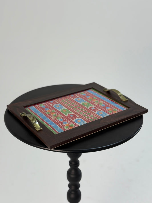 Large wooden serving tray with hand-stitched rich geometric embroidery in vibrant colors, crafted by Palestinian women artisans.
