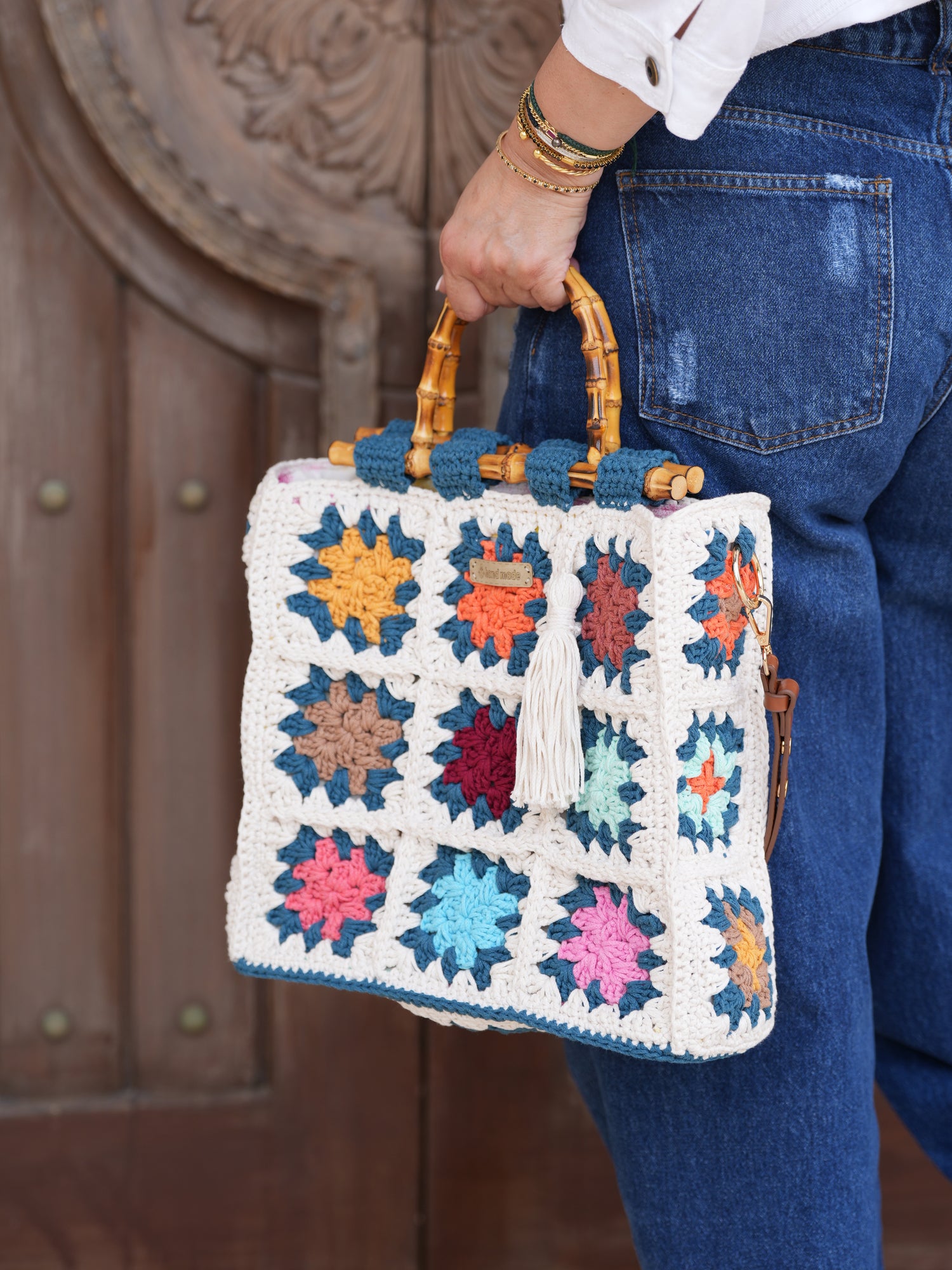 Handmade crochet granny square bag in teal, off-white, and multicolor with bamboo handles, limited edition artisan accessory