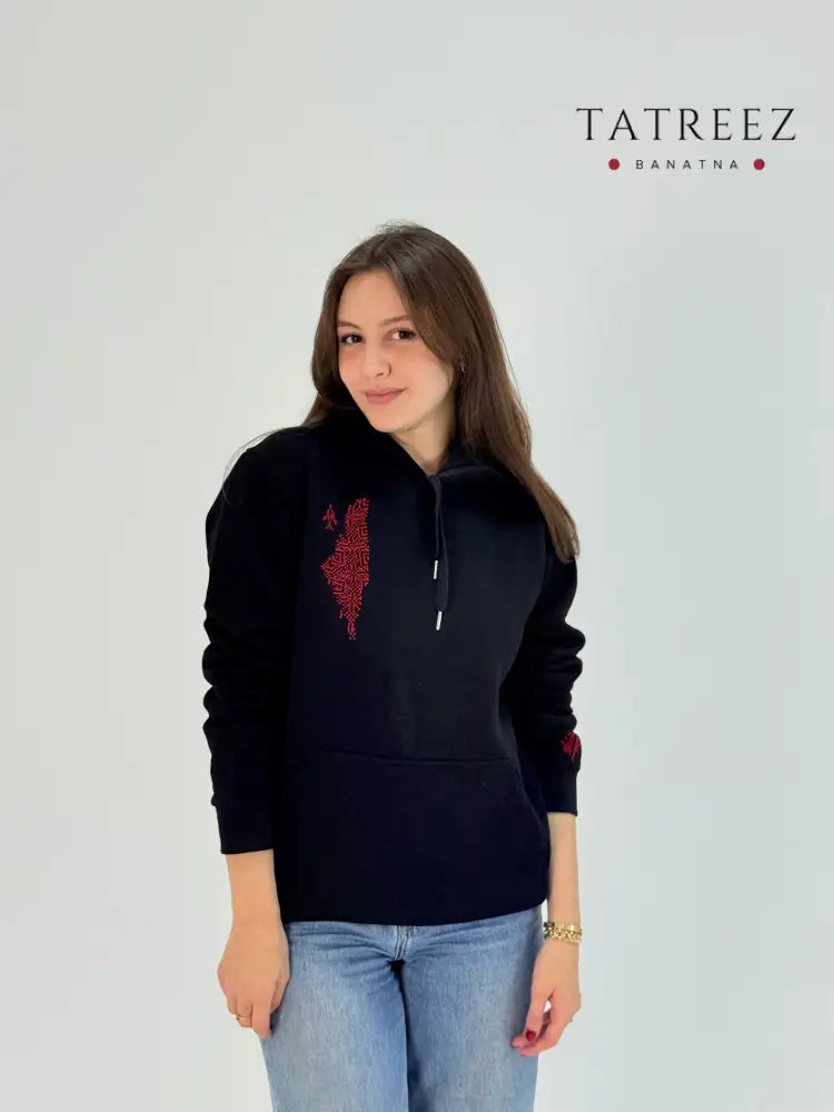 Black cotton hoodie with hand-embroidered red Palestinian map and tatreez design, modeled with jeans, handmade by women artisans