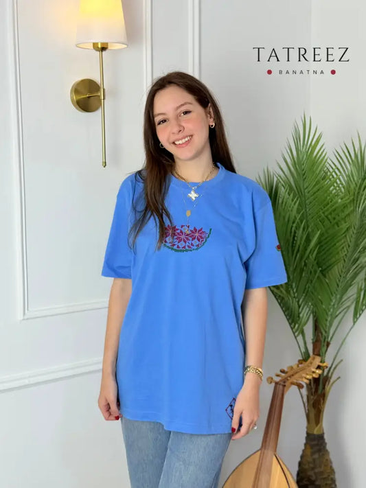 Light blue cotton t-shirt with handmade Palestinian watermelon embroidery, modeled with jeans, crafted by women artisans