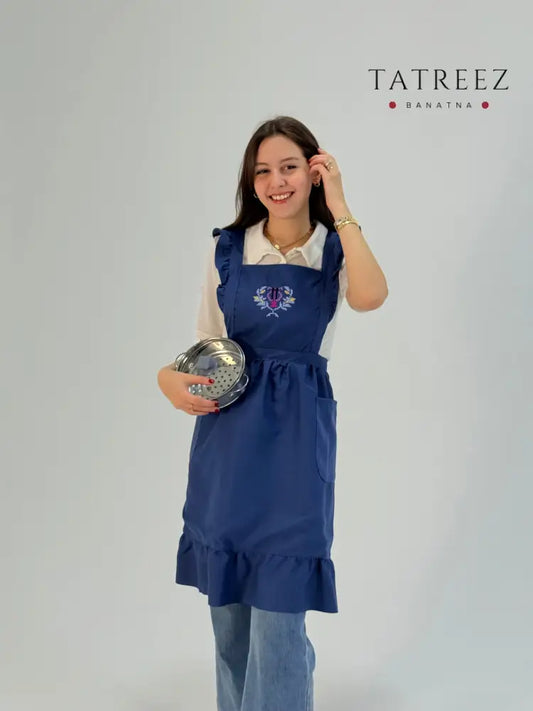 Blue waterproof apron with handmade Sanable floral embroidery, crafted by women artisans.