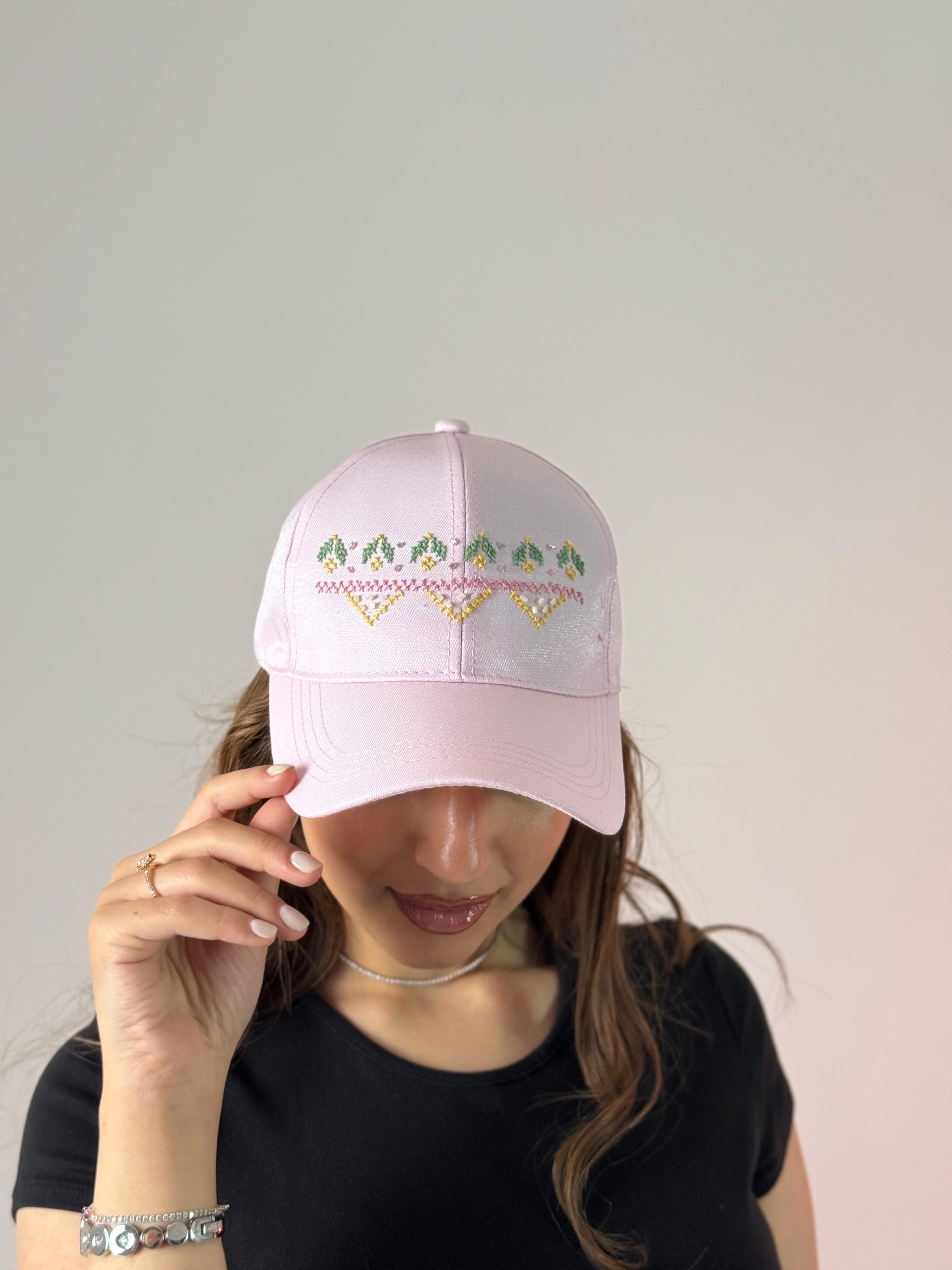 Pink hat with simple embroidery of small mountains and flowers.
