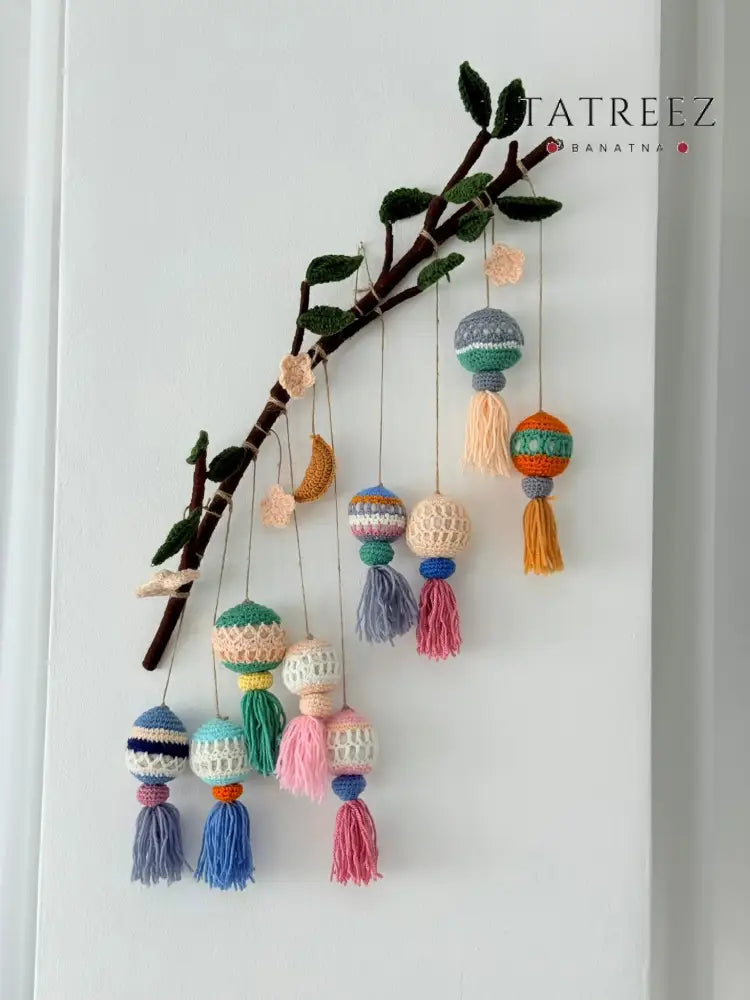 Handmade crochet Eid decoration featuring colorful lanterns, moons, and stars with tassels hanging on a branch, crafted for festive Ramadan and Eid decor.