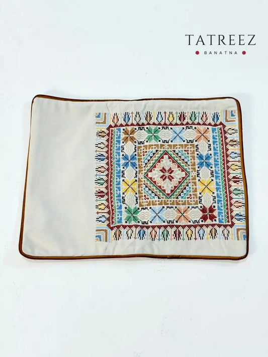 Hand-embroidered rectangular cushion covers featuring vibrant Palestinian tatreez geometric motifs on beige and turquoise backgrounds, crafted by women artisans from Palestine and Jordan to preserve heritage and support their livelihoods.