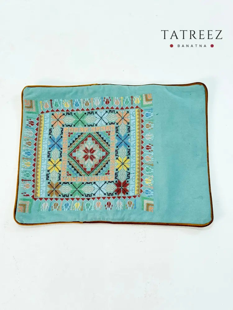 Hand-embroidered rectangular cushion covers featuring vibrant Palestinian tatreez geometric motifs on beige and turquoise backgrounds, crafted by women artisans from Palestine and Jordan to preserve heritage and support their livelihoods.