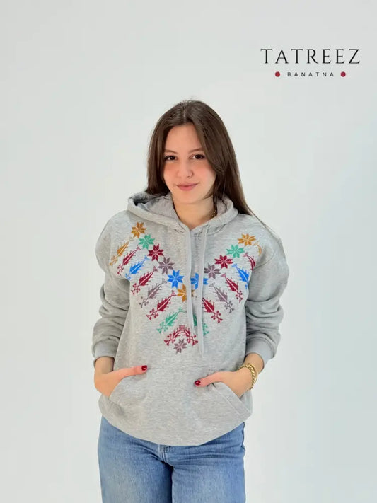 Light grey cotton hoodie with colorful Kanaan star hand embroidery, handmade by women artisans in Palestine and Jordan.